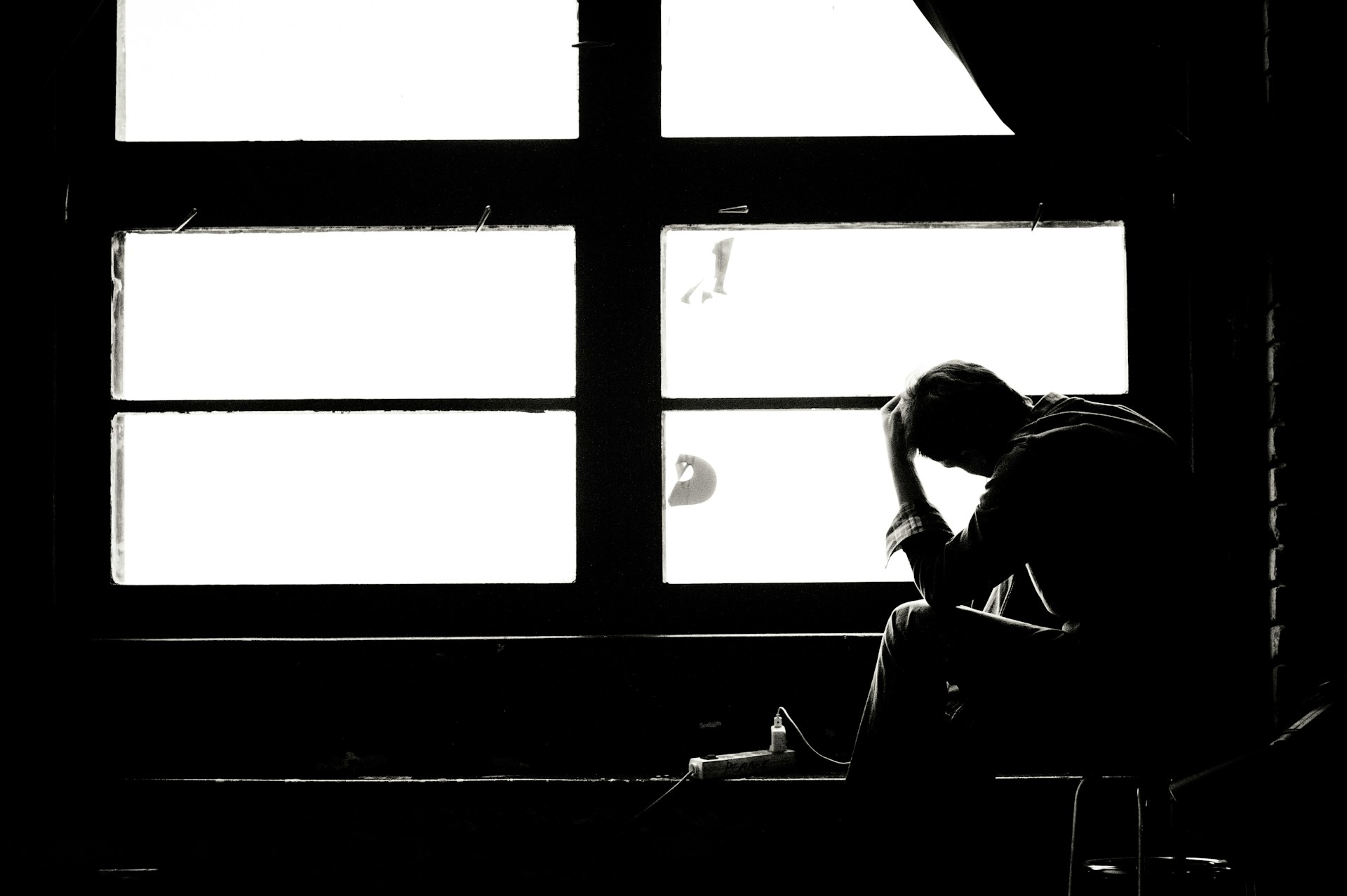 Does Peyronies go away on its own, or is it chronic? Man sitting alone by a window, wondering whether Peyronie's disease will go away on its own or become chronic